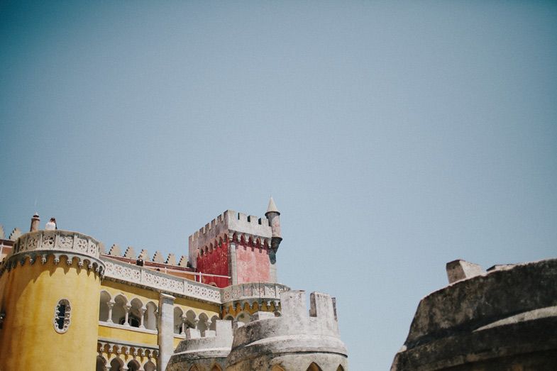 Red and yellow towers of Pena Palace rising against a bright blue sky in Sintra.