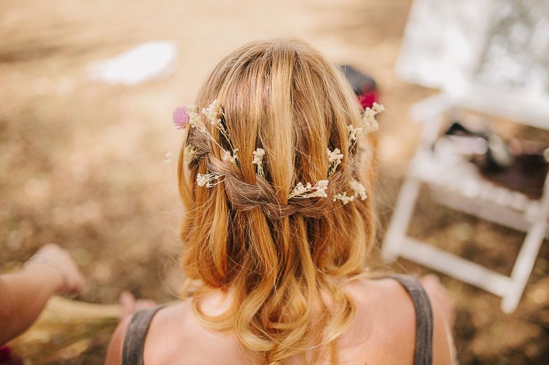 An elegant bridal hairstyle adorned with flowers and braids shown from behind.