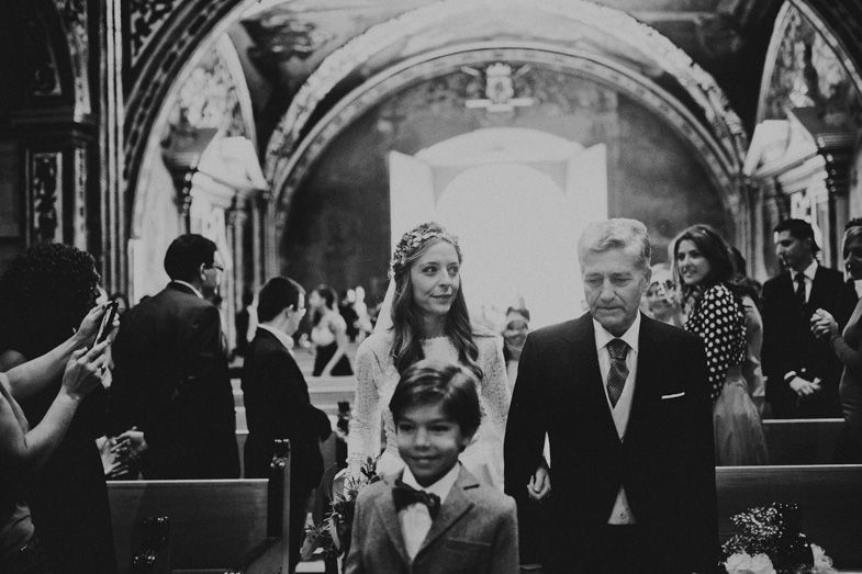 A black and white photo captures wedding party members walking through a church after the ceremony.