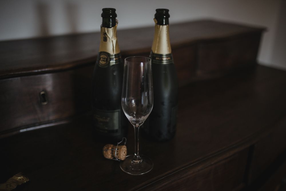 Two champagne bottles and an empty wine glass on a dark wooden surface.
