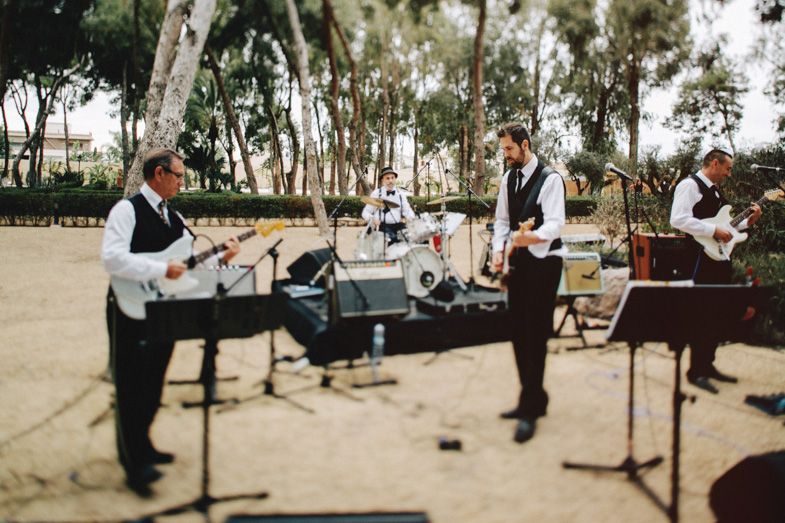 Live band performing at outdoor wedding with instruments and equipment set up.