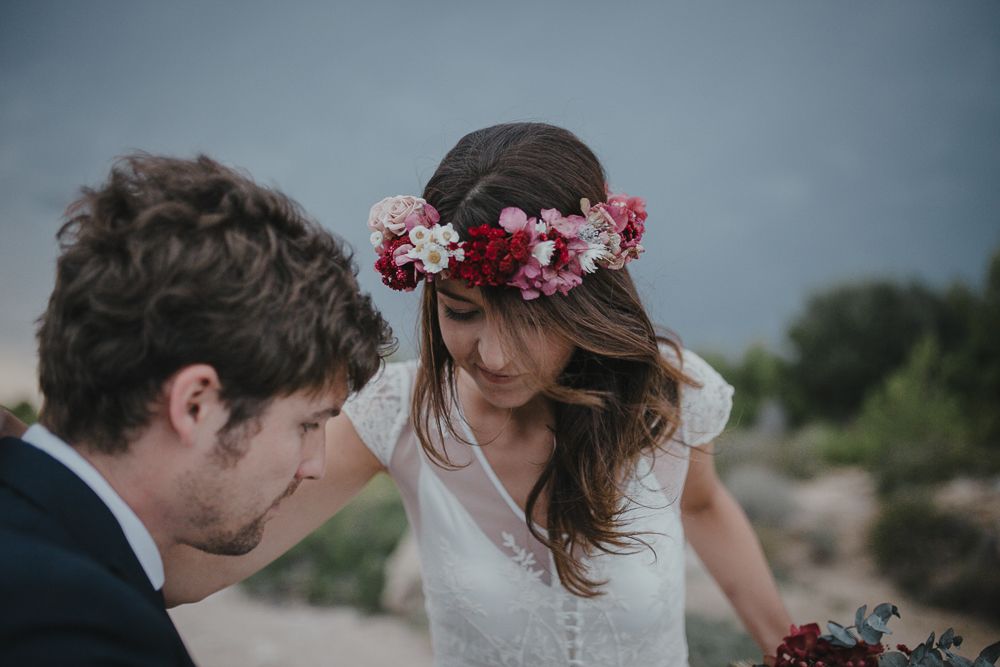 A tender moment between newlyweds on coastal rocks with flower crown details.