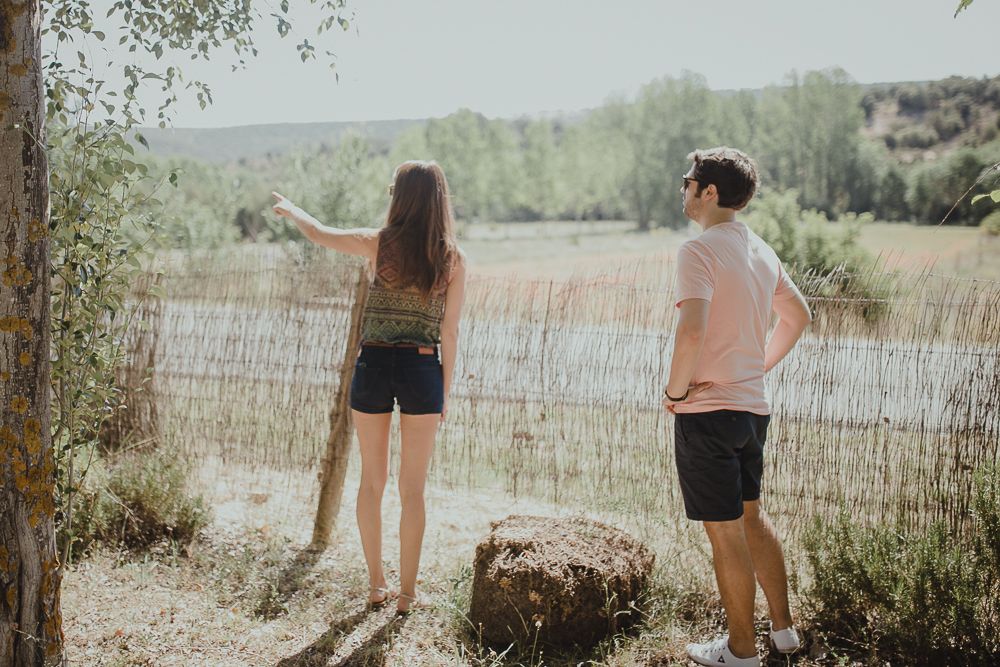 Couple enjoying a scenic view by a lake with summer foliage in the background.