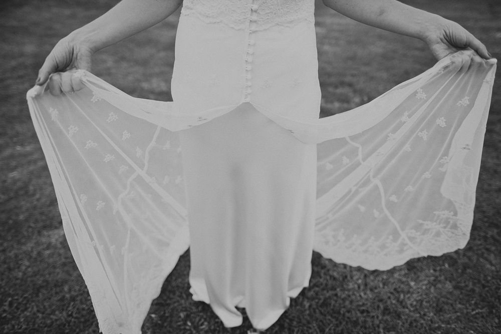 Black and white detail shot of lace wedding dress fabric being held out.