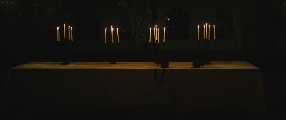 A row of lit candles creates a dramatic mood on a dark surface.