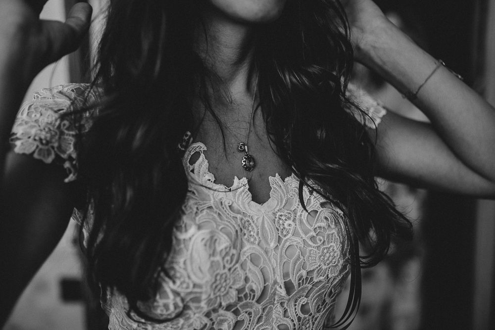 Close up detail of delicate white lace pattern on a dress with long dark hair.