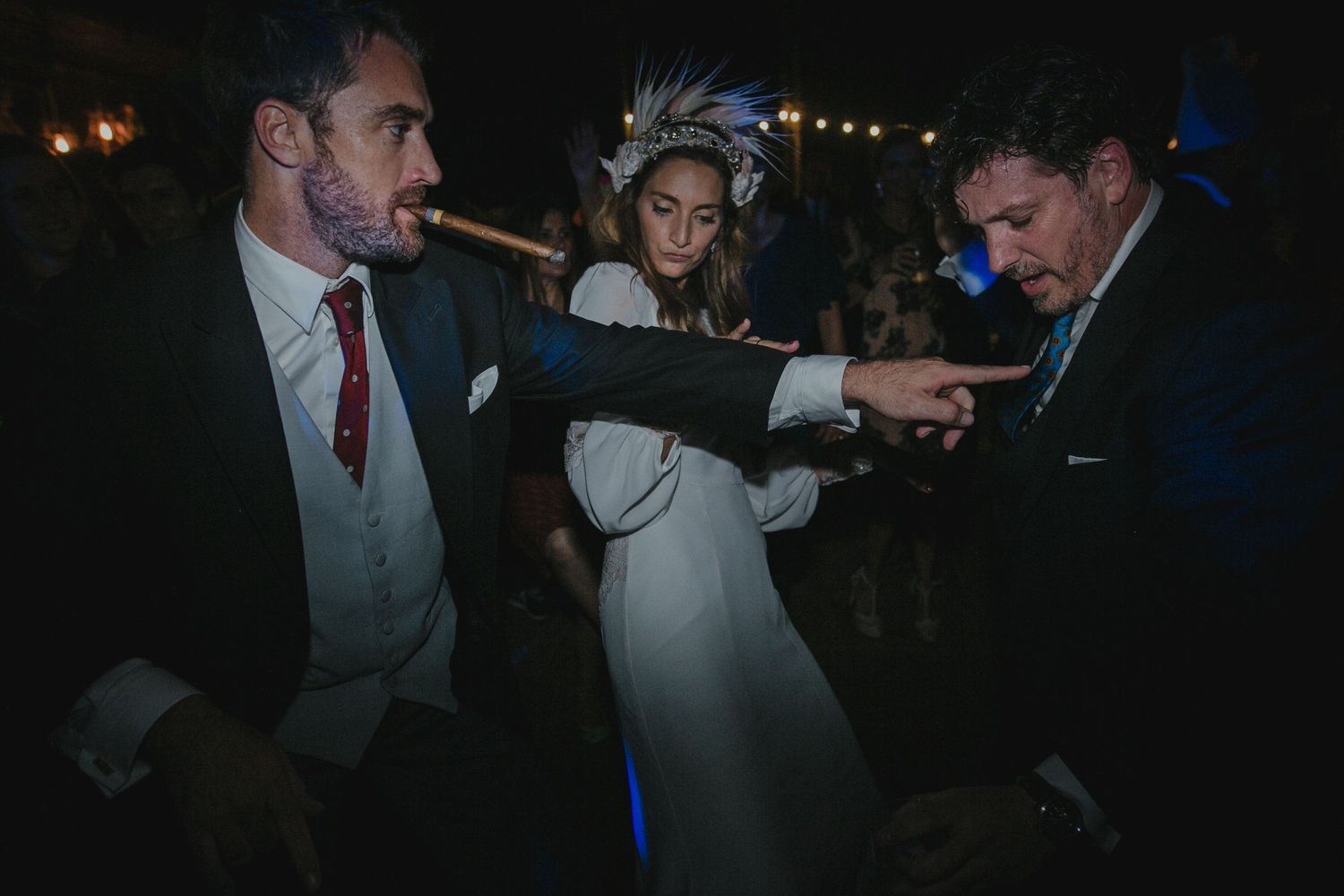 Wedding guests dancing together at a dimly lit reception.