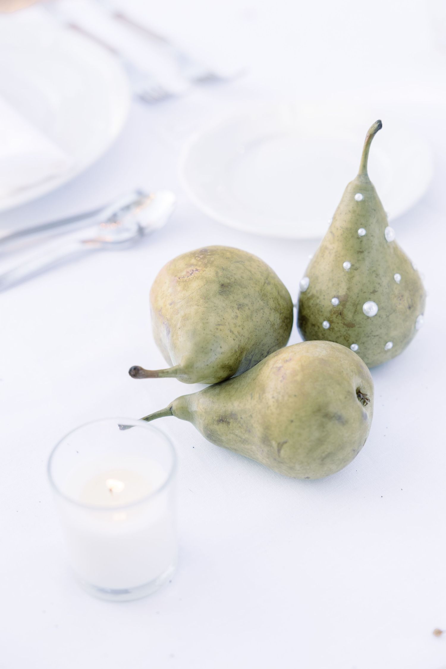 Artistic still life of fresh pears on white linen tablecloth.