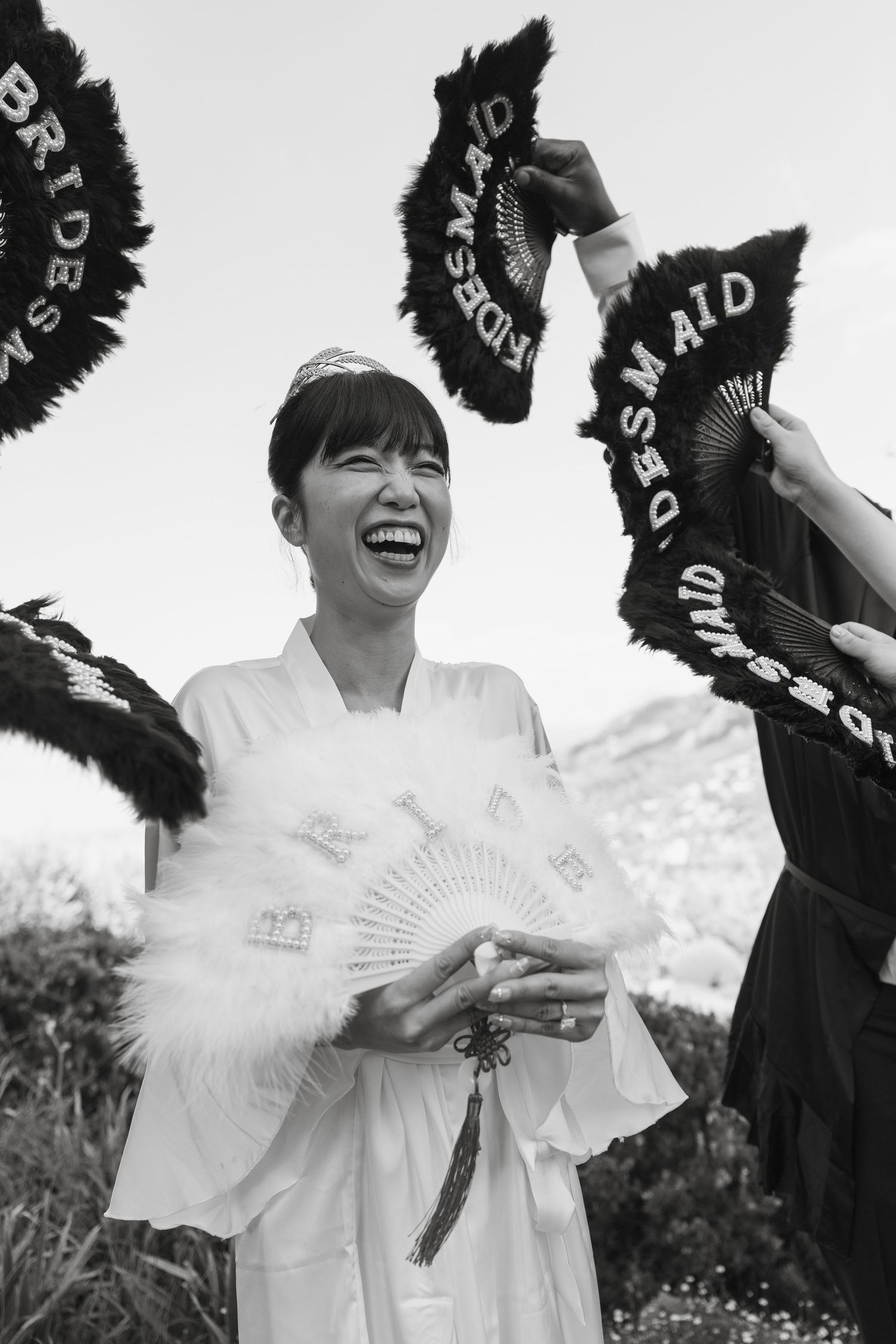 Black and white photo of joyful moments with decorative fans at outdoor celebration.