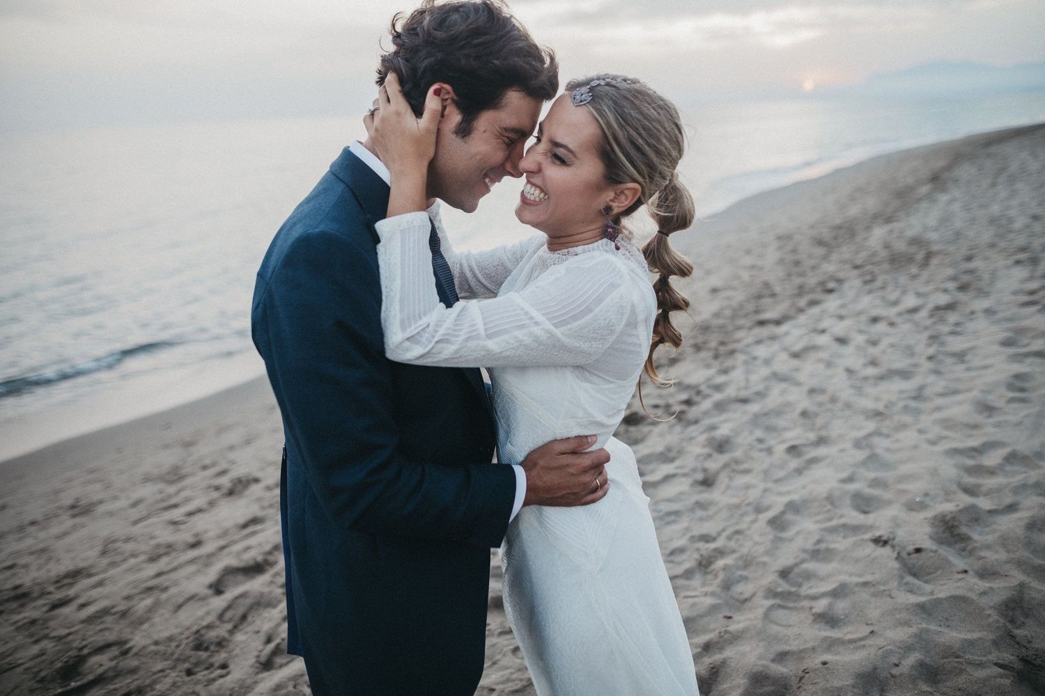 Intimate beach wedding portrait at sunset with couple in formal attire.