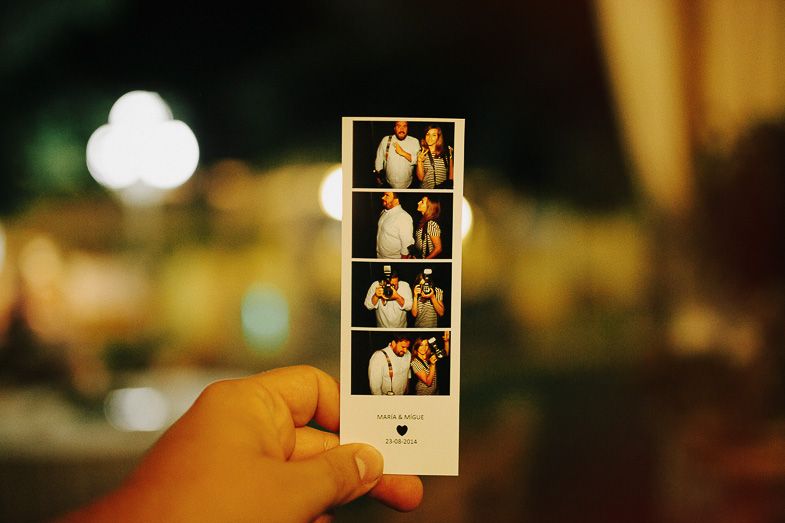Hand holding a photo booth strip showing wedding moments in black and white.