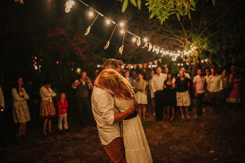 Couples dancing under romantic string lights at an outdoor evening celebration.