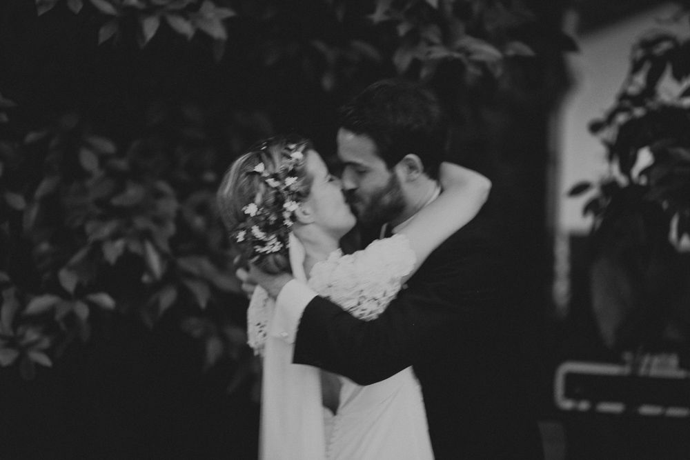Intimate black and white portrait of newlyweds sharing romantic moment under trees.