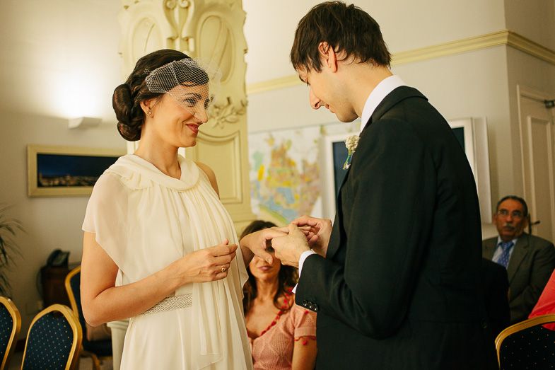 Couple exchanging rings during intimate indoor wedding ceremony.