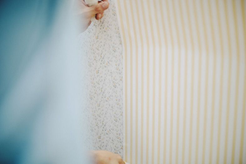Close-up view of wallpaper being removed showing striped pattern underneath.