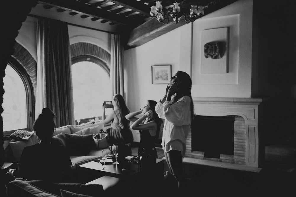People relaxing in an elegant room with arched windows and a fireplace.
