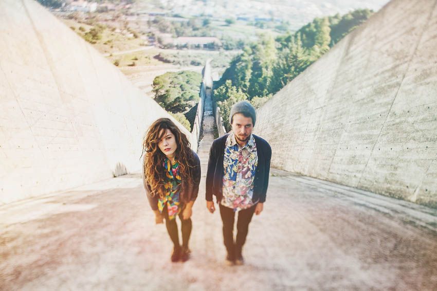 Couple walking together on a steep concrete path with city vista in background.