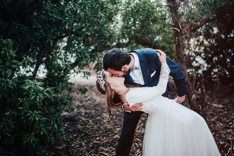 Romantic dip pose among trees in natural outdoor wedding setting.