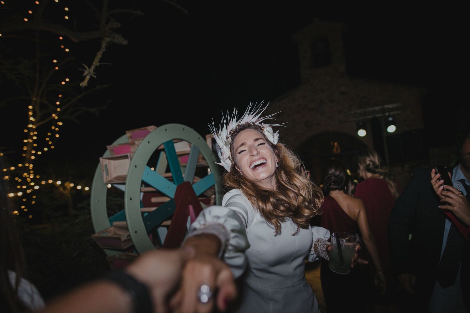 Celebratory dance scene with string lights and decorative wheel in background.