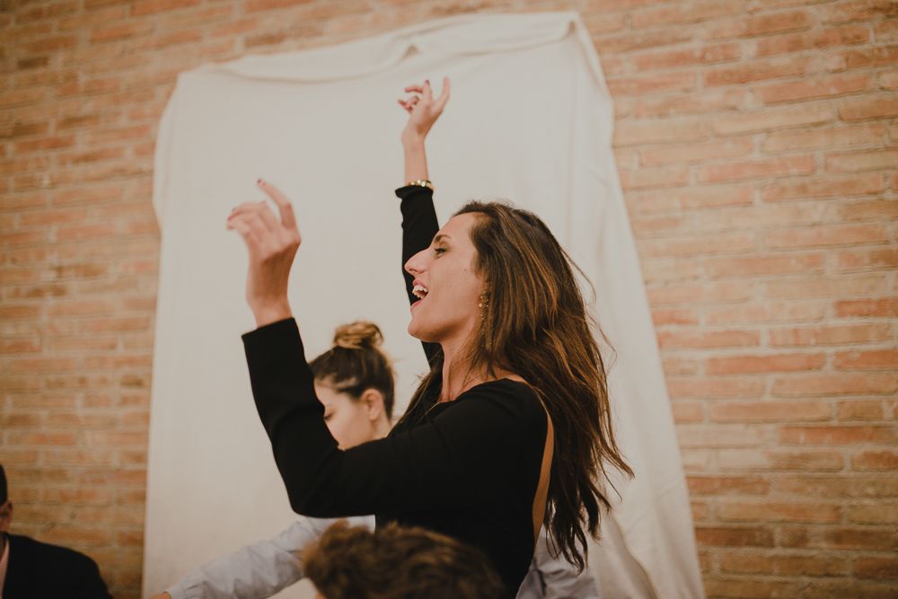 Dancing guest celebrating with raised arms against brick wall.