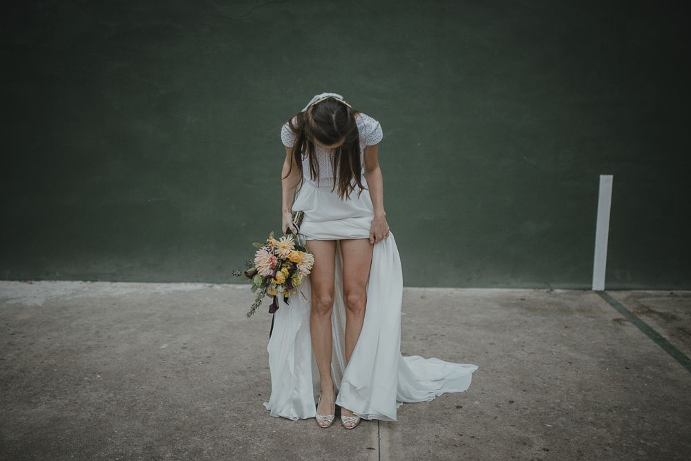 Artistic wedding photo showing dress details and bouquet against green background.