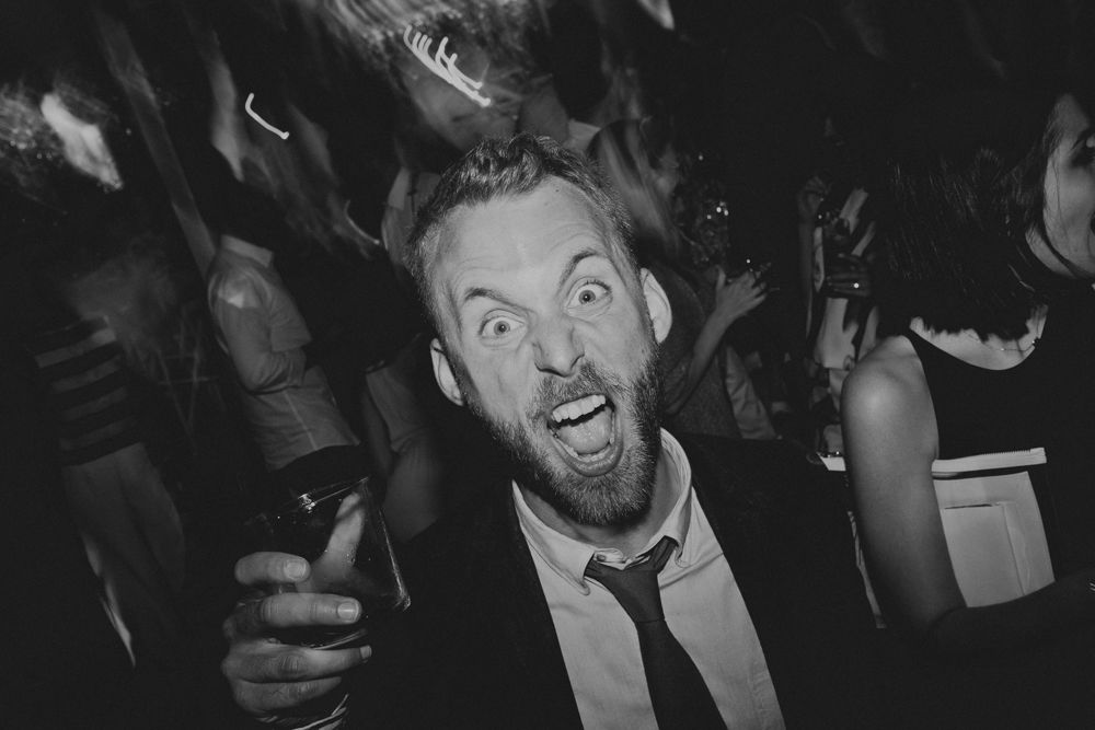 Excited party guest in tie shows animated expression in black and white photograph.