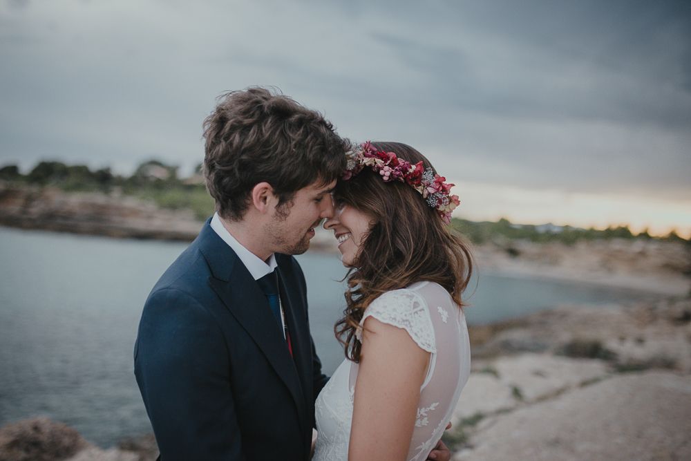 A romantic moment between a couple on rocky coastal cliffs at sunset.