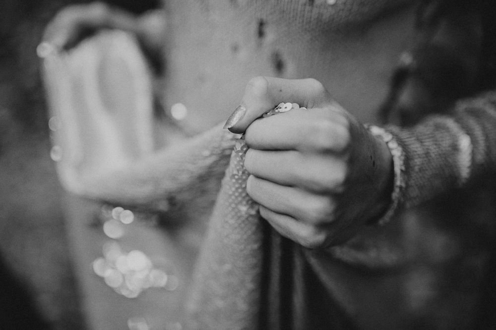 Black and white close-up of hands working with fabric in soft focus.