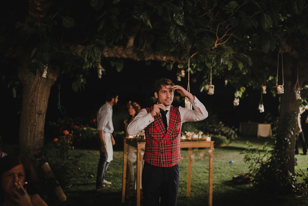 Person in a red vest performs outdoors under hanging lanterns at night.