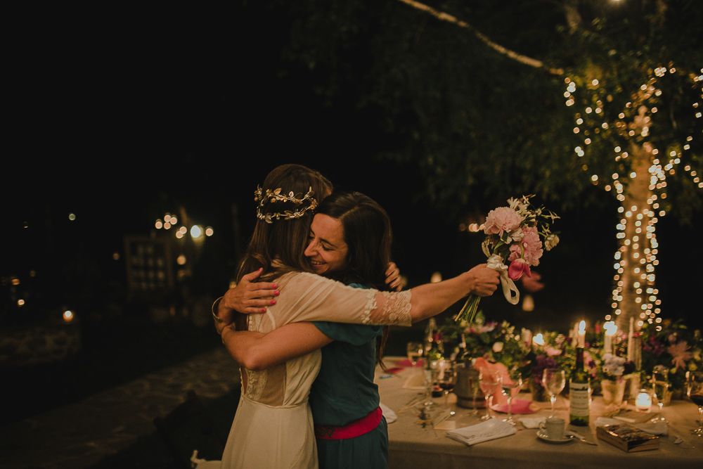 A warm embrace shared during an evening wedding celebration with string lights in the background.
