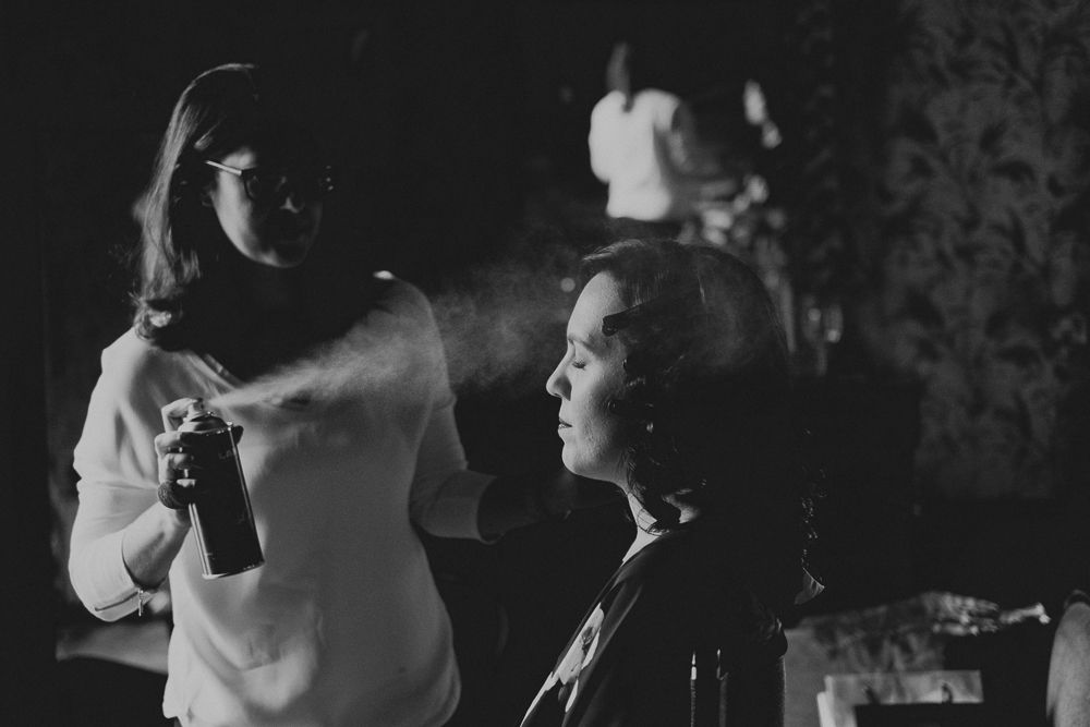 Hair styling preparation captured in black and white with dramatic lighting.