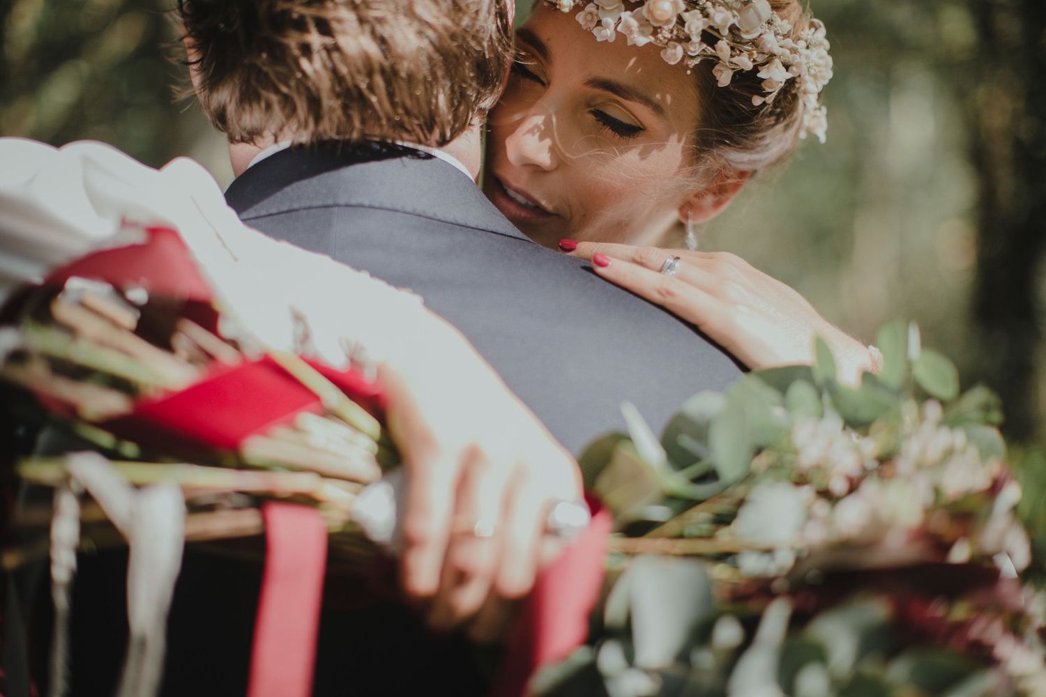 An intimate embrace captured in warm sunlight with a floral bouquet and delicate headpiece.