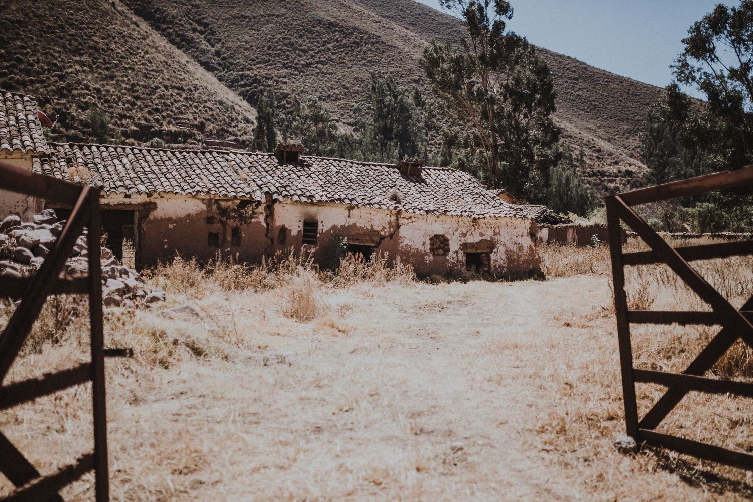 A rustic wooden gate entrance leading to an old stone building in a desert landscape.