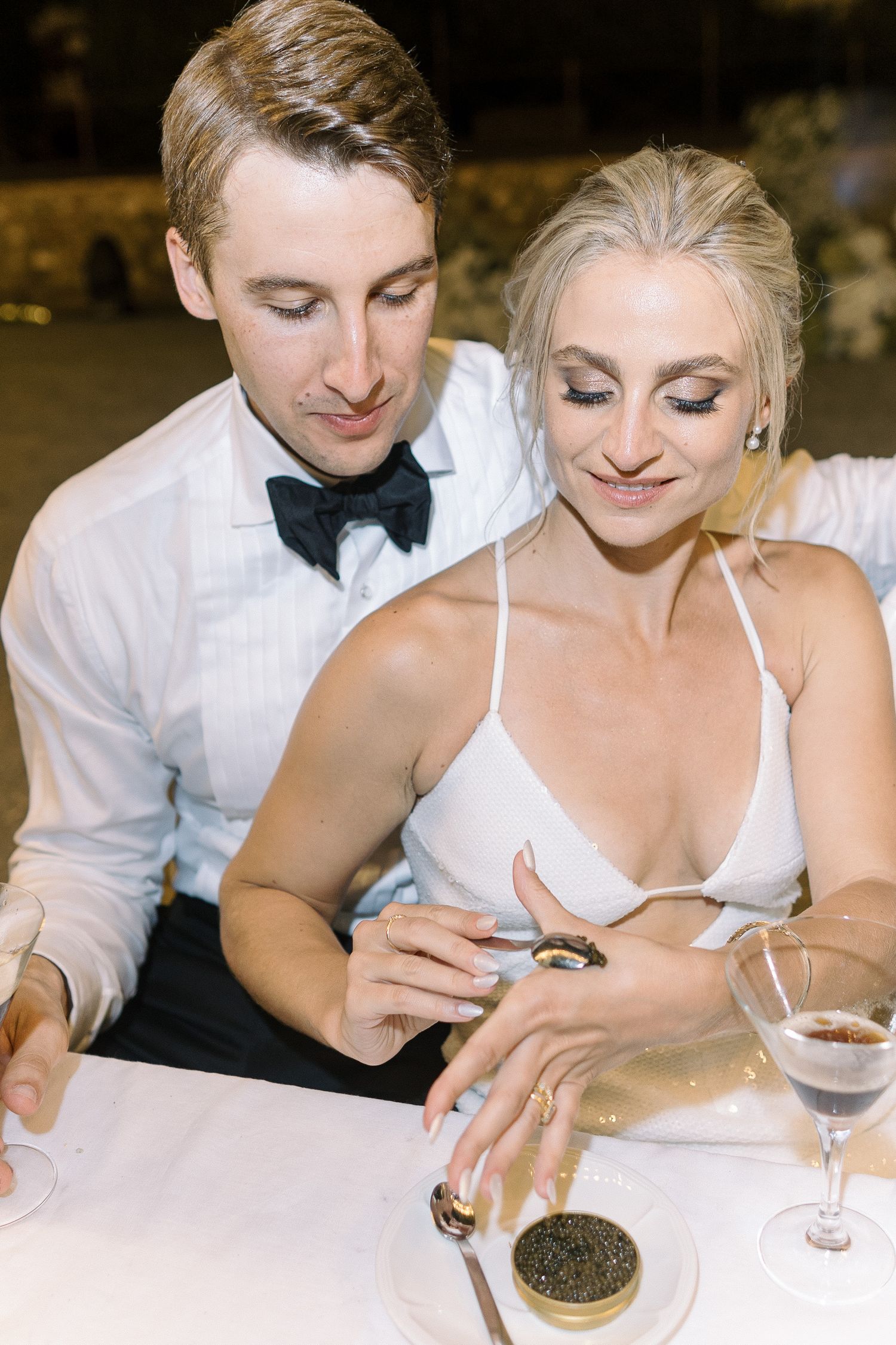 Couple enjoying caviar and wine at an intimate dinner table setting.