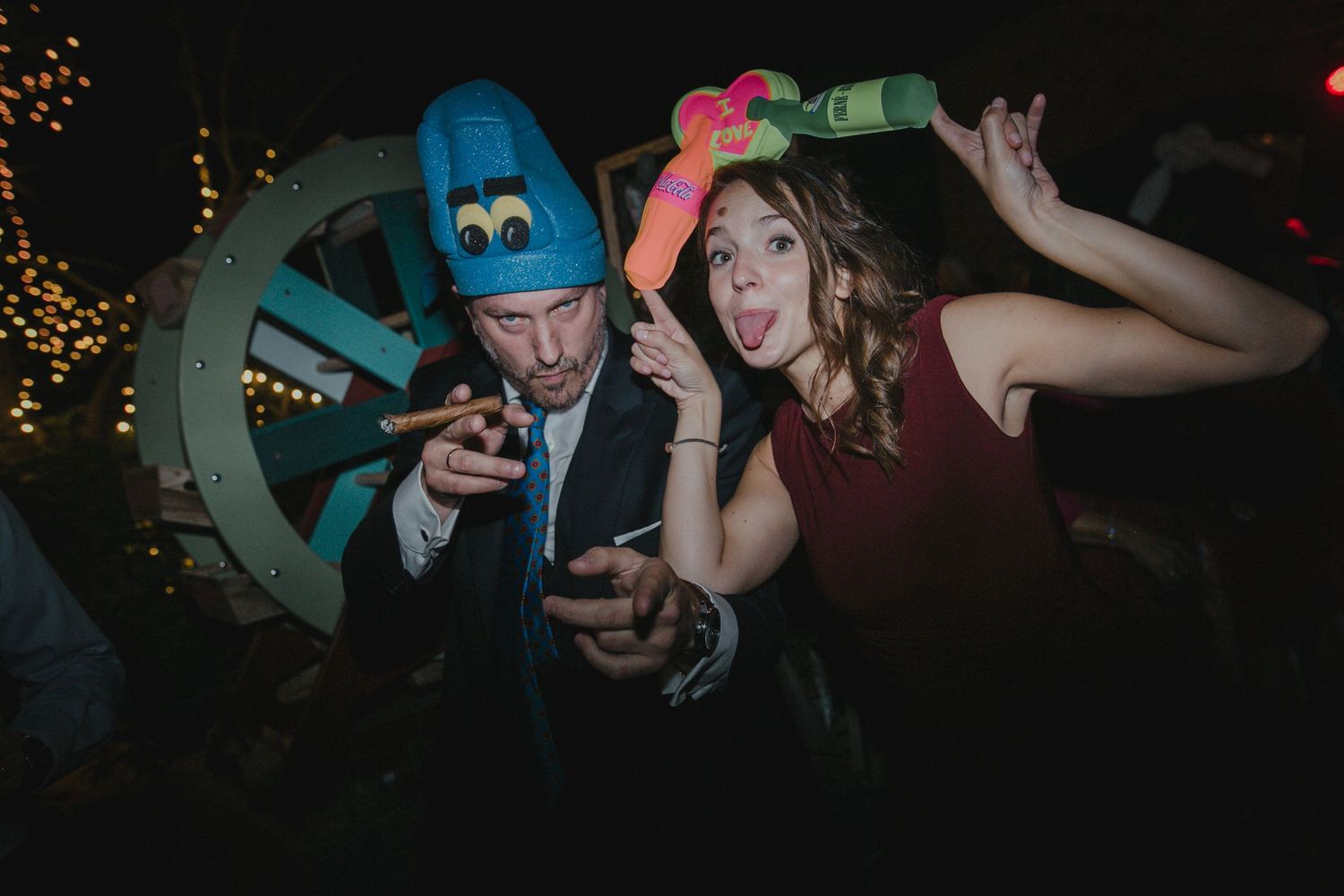 Party guests in playful costumes pose with props at nighttime celebration.