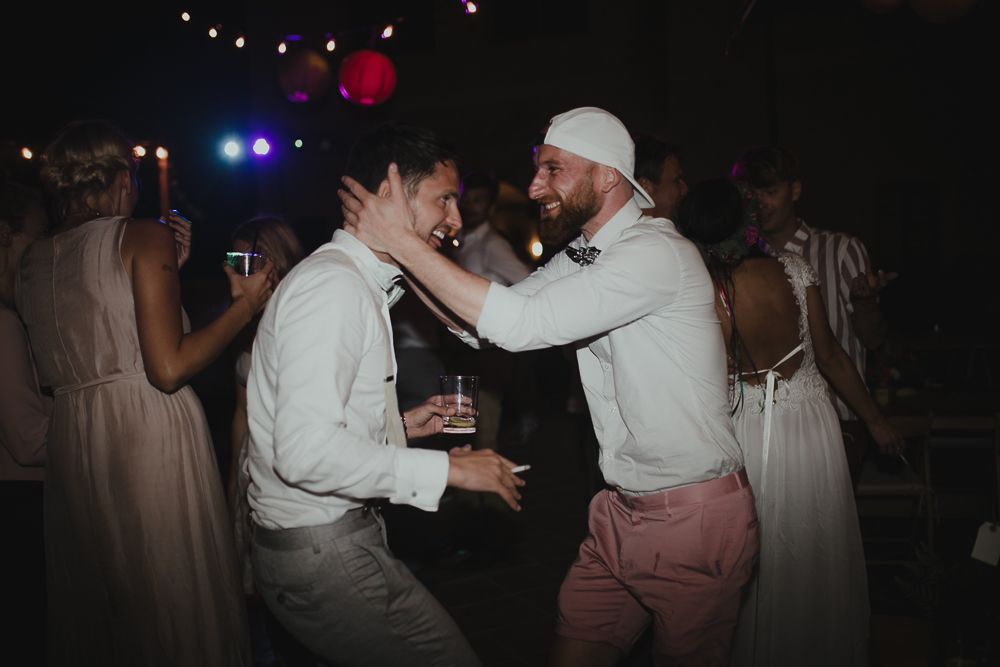 Two party guests dancing enthusiastically at a dimly lit reception with string lights overhead.