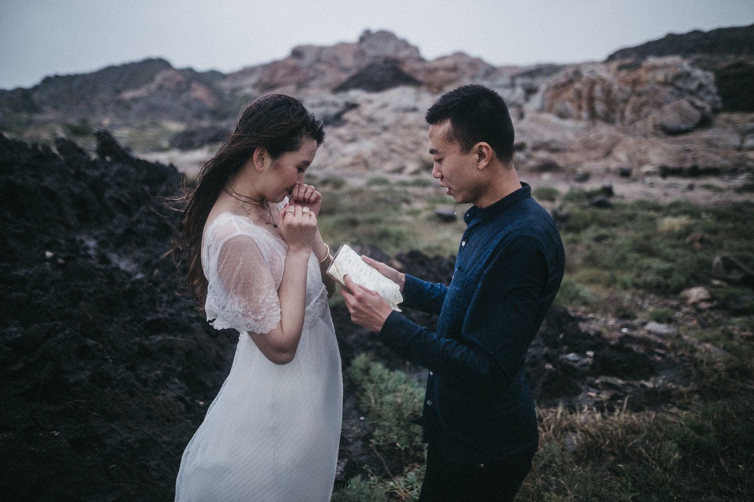A couple shares an intimate moment during their outdoor wedding ceremony against a backdrop of rugged mountains.