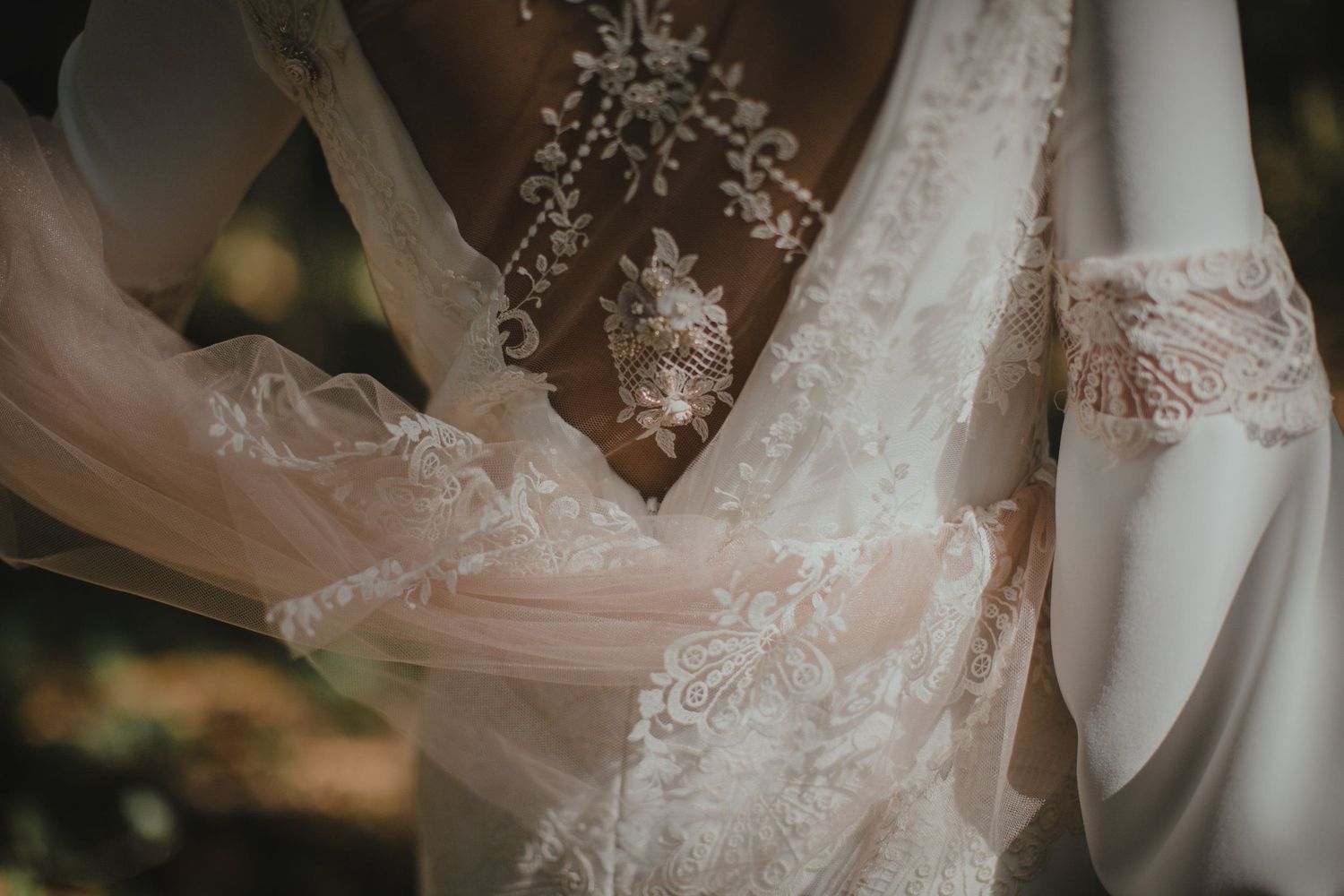 Delicate lace detailing on a white wedding dress captured in soft natural light.