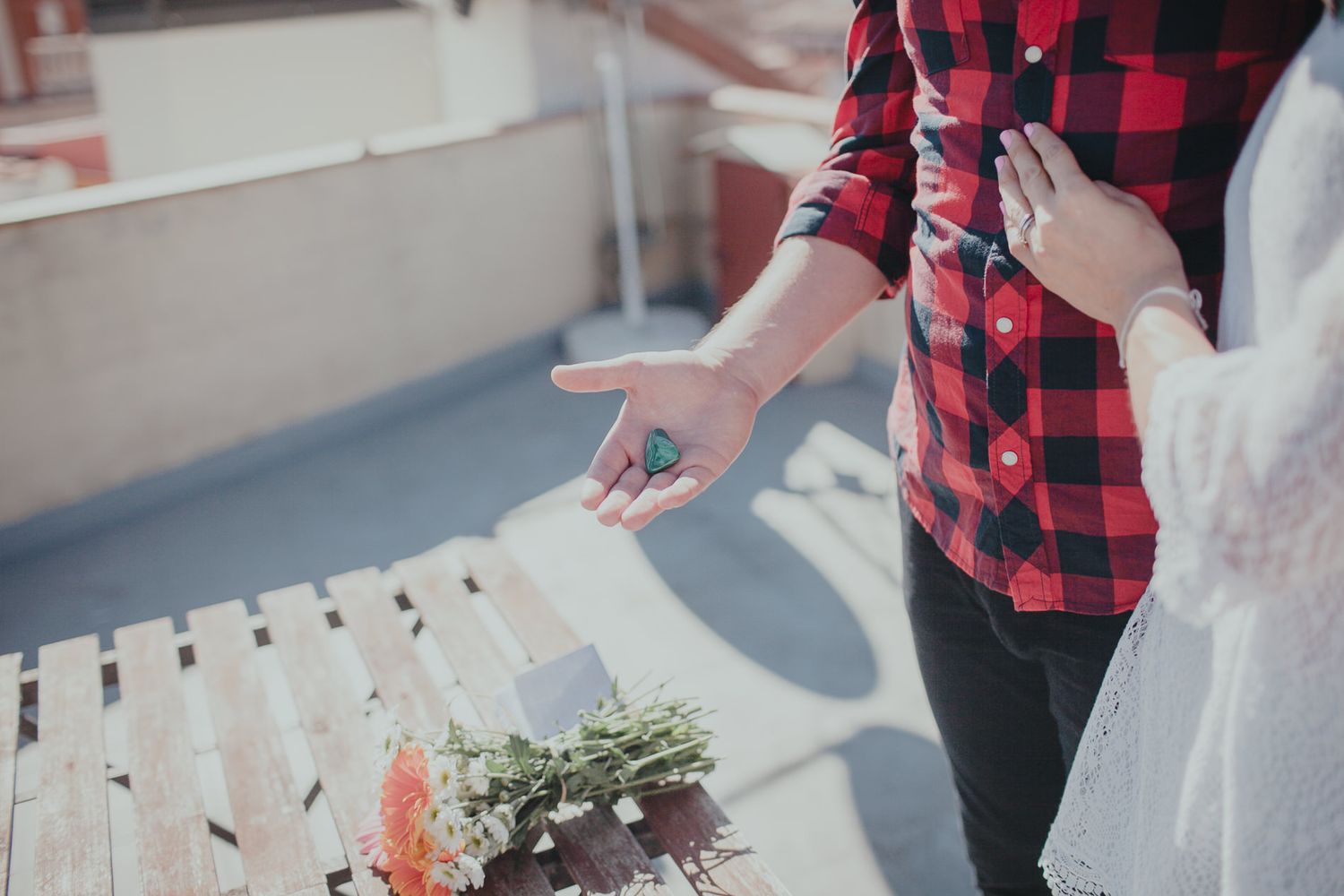 Hands gesturing over decorative flowers on a rooftop terrace.