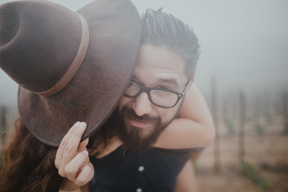 A cozy moment shared between two people wearing a brown felt hat.