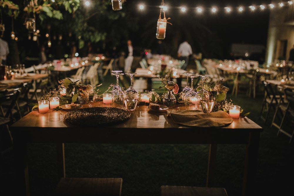 Wedding reception table decorated with string lights and floral centerpieces at dusk.