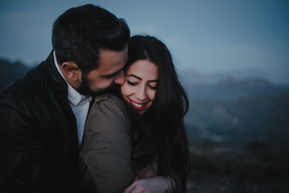 A tender embrace captured in silhouette against a dusky mountain backdrop.