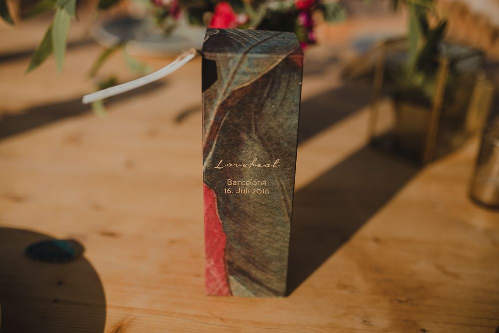 Dark geometric wedding invitation or card on wooden surface with greenery.
