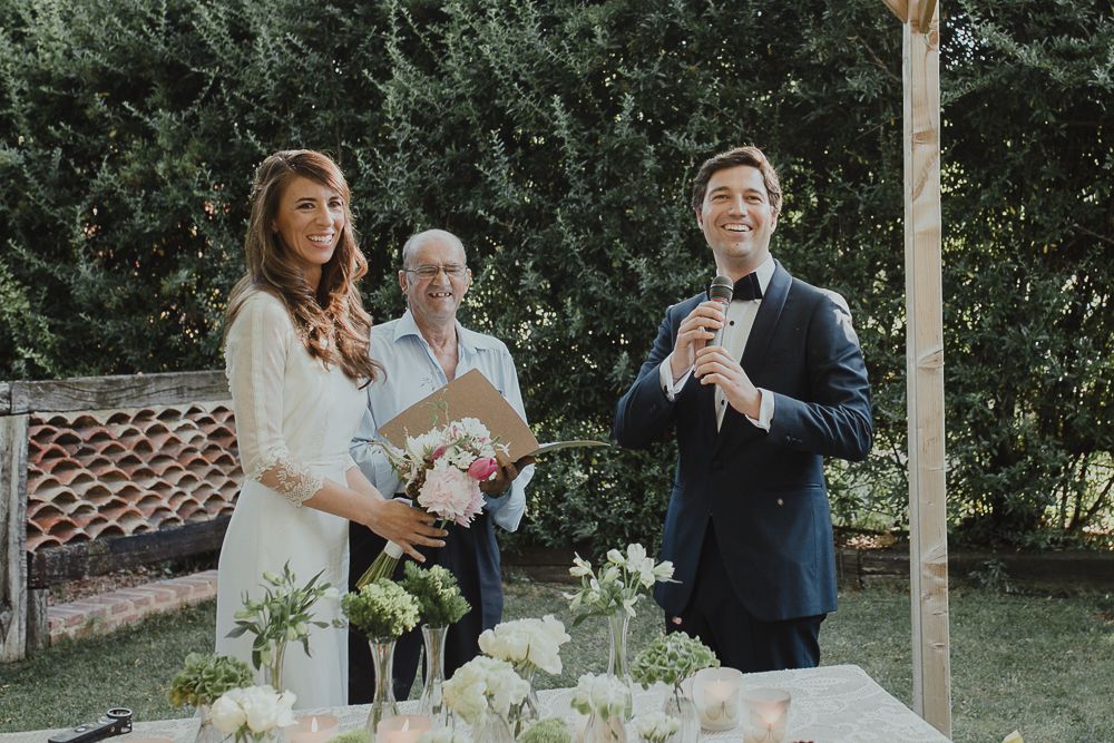 Couple stands at altar during outdoor garden wedding ceremony with floral arrangements.