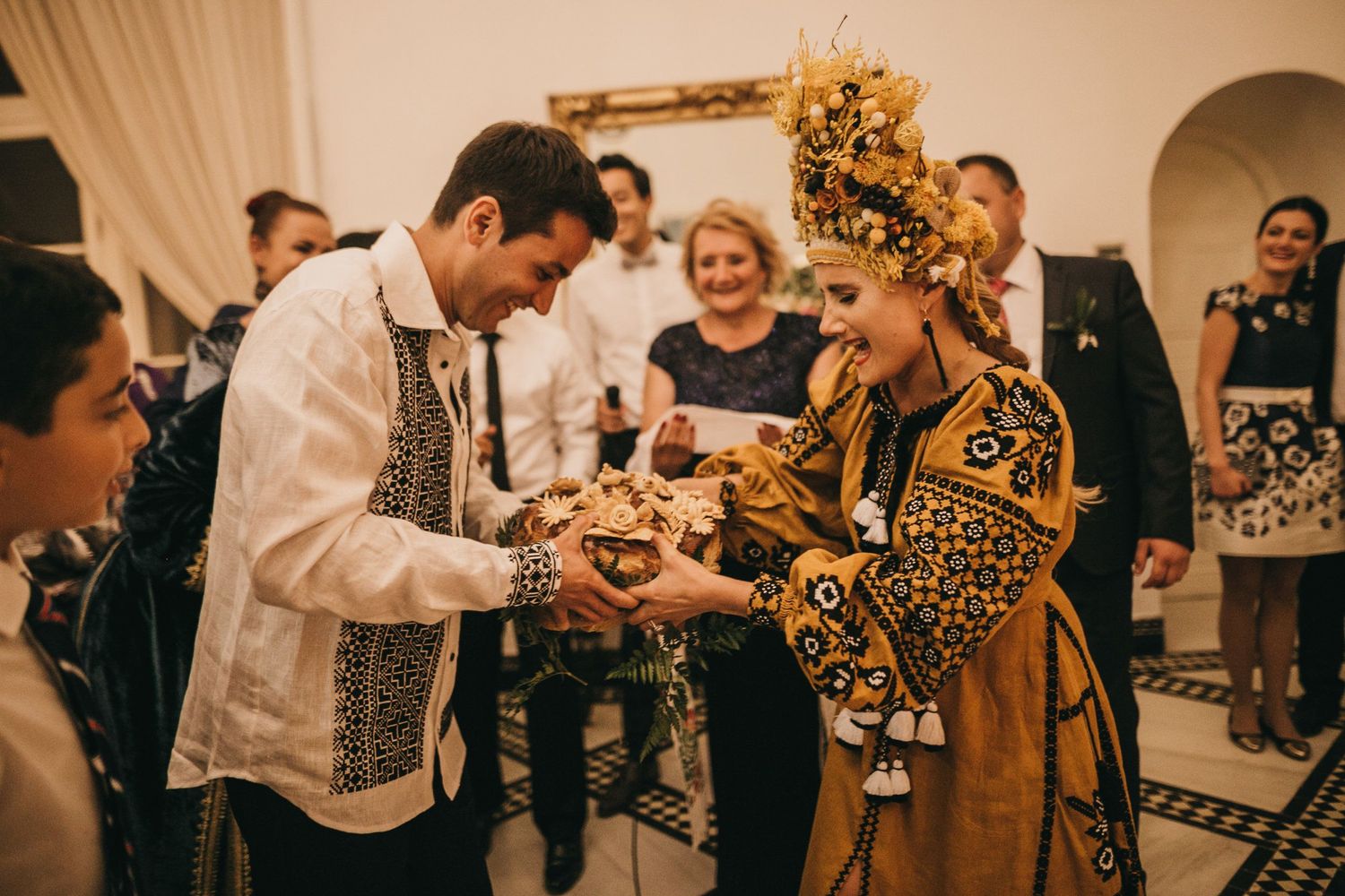 Traditional wedding ceremony with guests watching exchange of rings in decorated indoor venue.