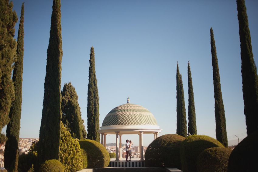 Classical domed gazebo surrounded by tall cypress trees in a manicured garden.