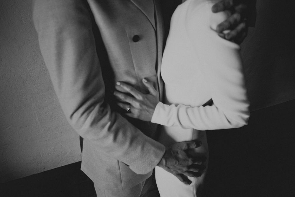 Artistic black and white close-up of a couple embracing, showing formal attire and intimate body language.