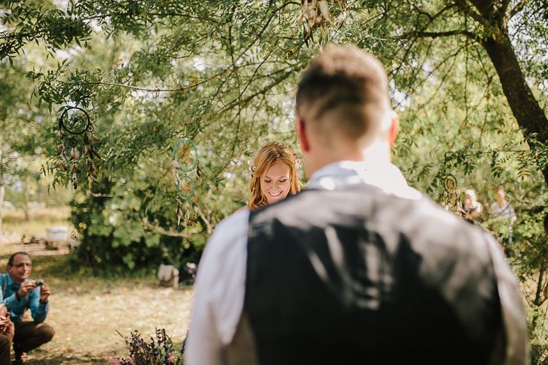 An intimate wedding moment captured in a sunlit garden with trees in the background.