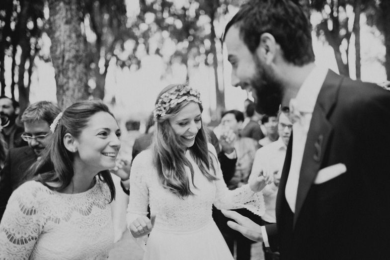 Candid black and white photo of wedding guests laughing during outdoor celebration.
