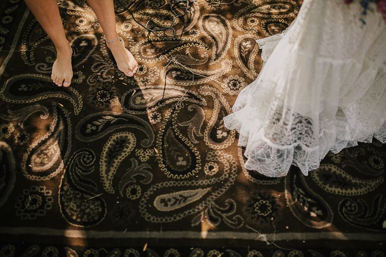 White lace dress fabric contrasts against an ornate dark patterned carpet.